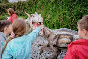 Kids playing with a dinosaur outside